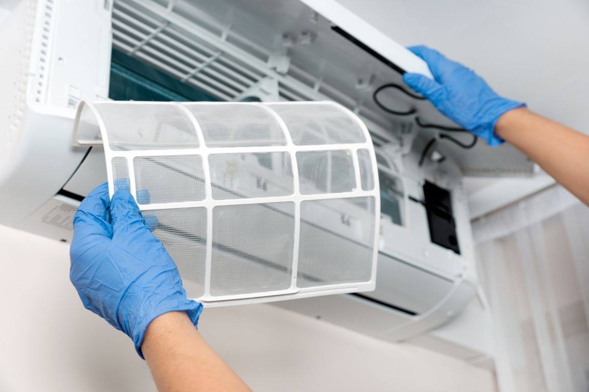 Technician cleaning an air conditioner filter to improve energy efficiency